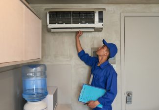 Young Asian technician checking conditioner in kitchen